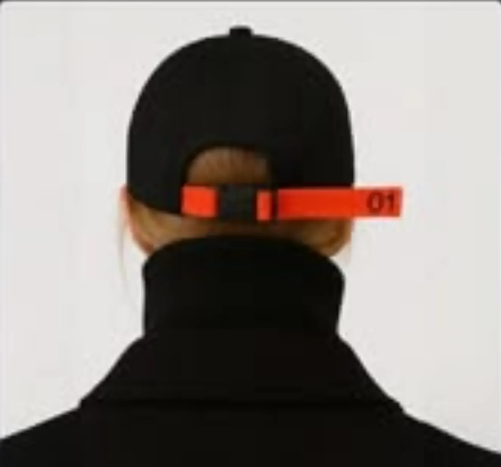 Rear portrait with a black cap and a vivid red strap