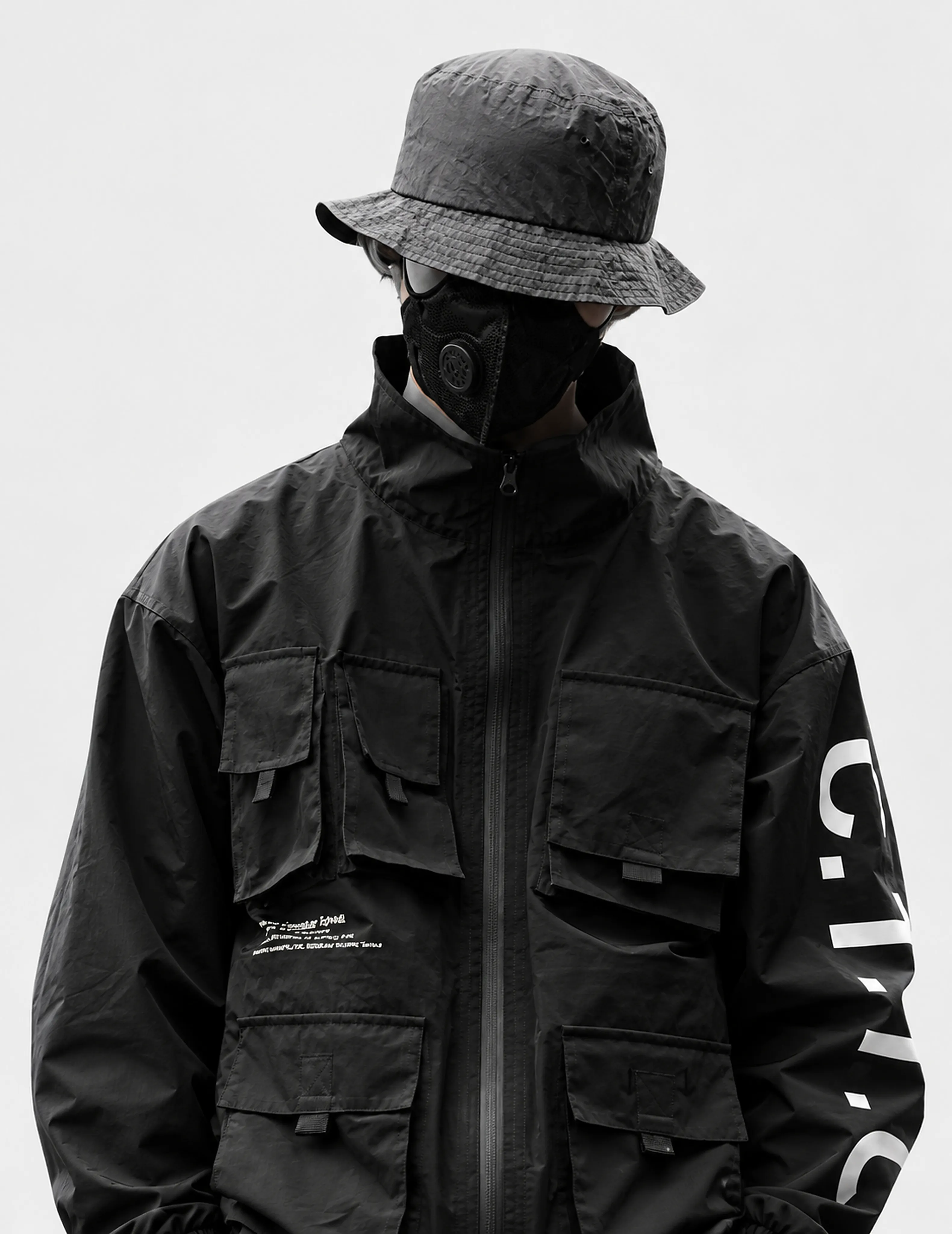 Masked figure in sculptural technical streetwear and a grey bucket hat
